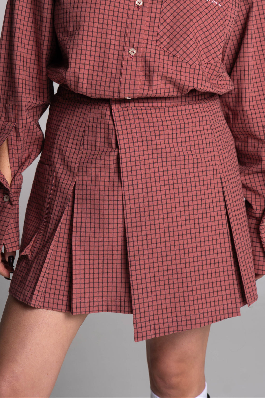 Person wearing a red checkered outfit with a shirt and skirt on a gray background