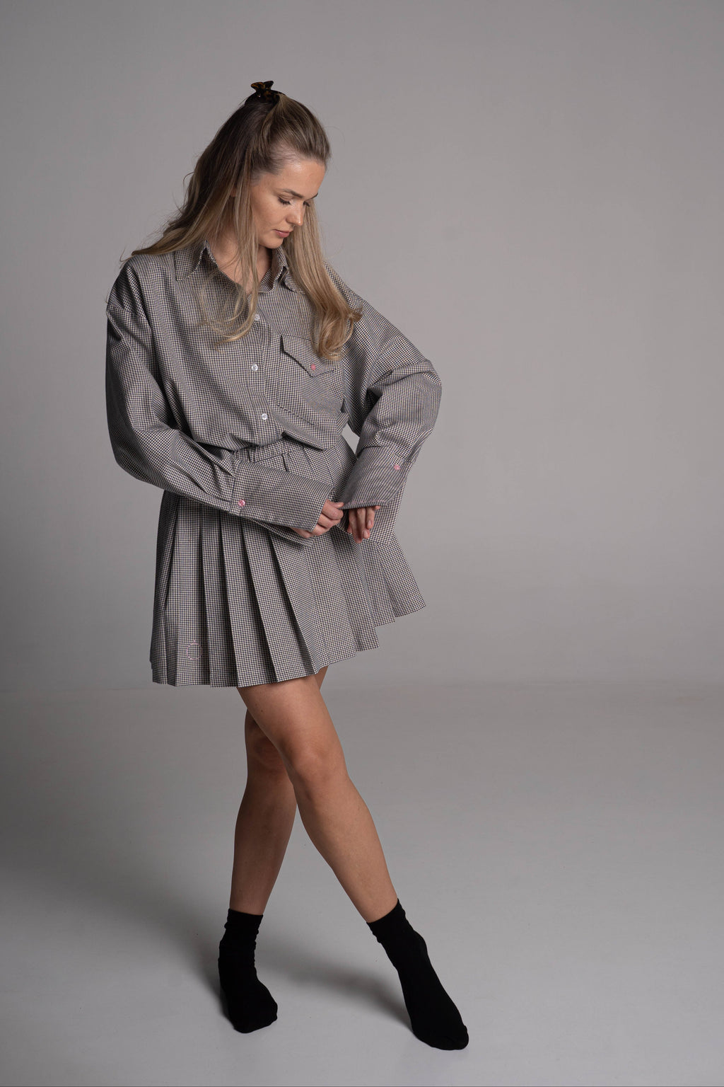 Woman wearing a navy beige check outfit on a plain background